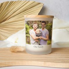 a candle with an image of two men holding a baby in it on top of a wooden table