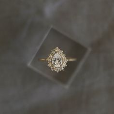 an engagement ring sitting on top of a glass block in front of a gray background