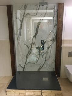 a bathroom with marble walls and flooring in the shower area, along with a toilet