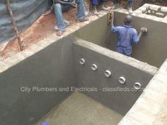 some people are standing around in a concrete pit that is being built into the ground