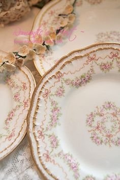 three plates with flowers on them sitting on top of a table next to some cookies