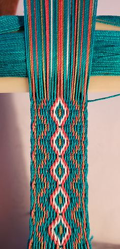 a close up of a piece of cloth on a wooden chair with beads and chains