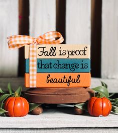 an orange pumpkin sitting on top of a wooden stand with a sign that says fall is proof that change is beautiful