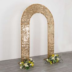 two vases filled with flowers sitting on top of a wooden floor next to an arch