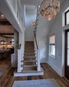 a staircase leading up to a kitchen and dining room area with chandelier hanging from the ceiling