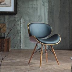 a black chair sitting on top of a hard wood floor next to a framed painting