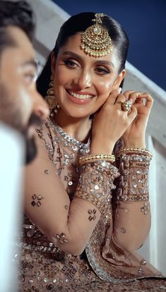 a woman in a bridal outfit smiles as she holds her hands to her face