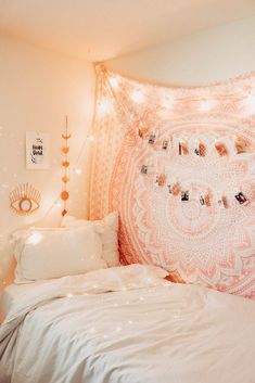 a white bed sitting next to a wall covered in pictures and string lights on top of it