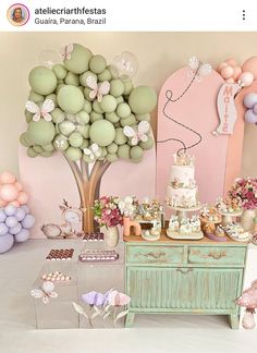 a table with balloons, cake and other decorations on it in front of a pink wall