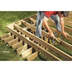 a man is working on some wooden beams in the grass with two hands holding tools