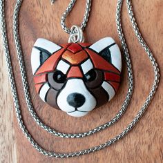 a necklace with a red, black and white animal face on it's chain