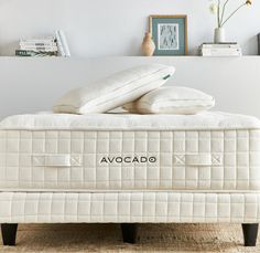 two pillows are on top of an avocado mattress in front of a bookcase