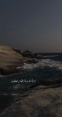 an image of the ocean and rocks with arabic writing on it in front of a dark sky