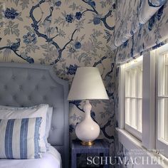 a bedroom with blue and white wallpaper and a bed in front of a window