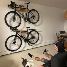 a man sitting on the floor in front of a dog and bike mounted to a wall