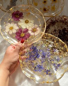 a person holding three plates with flowers on them