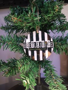 a black and white striped ornament hanging from a christmas tree with green leaves