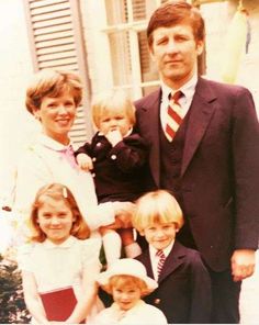 a man and two women are posing for a photo with their children in front of a house