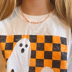 a girl wearing a halloween t - shirt with ghost and pumpkins on it