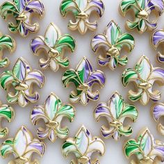 many different colored fleur de lis brooches on a white surface with gold trim