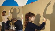 three people are drawing on the wall with their hands