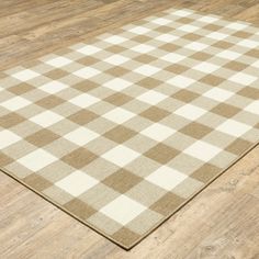 a brown and white checkered rug on top of a wooden floor in an empty room