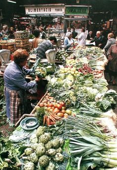 an outdoor market with lots of vegetables on display