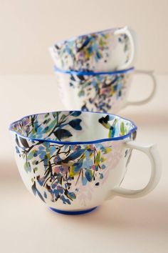 two white and blue cups with floral designs on the rims are sitting side by side