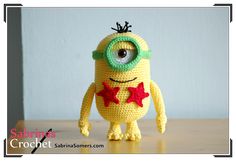 a crocheted yellow toy with green eyes and red stars