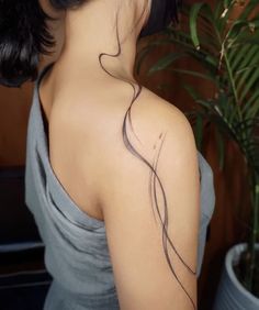 the back of a woman's neck with wavy lines on it and a plant behind her