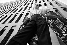 a man sitting on top of a skateboard in front of a tall skyscraper building