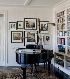 a living room with a piano and many pictures on the wall above it, along with bookshelves