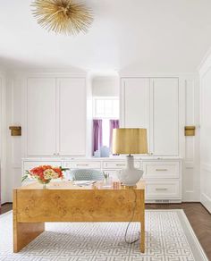 a white and wood desk in the middle of a living room with an area rug