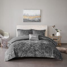 a bedroom with grey and white bedding in the corner, two chairs and a painting on the wall