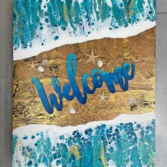 a painting with the word welcome painted on it in blue, gold and white colors