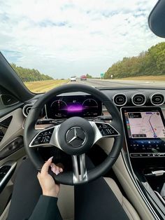 a person driving a car on the road with their hands on the steering wheel and dashboard