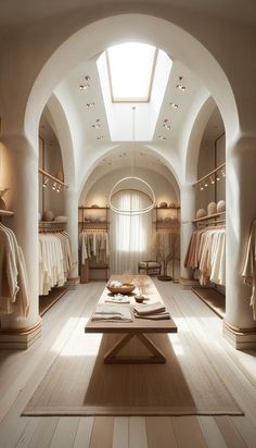 the interior of a clothing store with white walls and wood flooring is lit by sunlight streaming through the windows