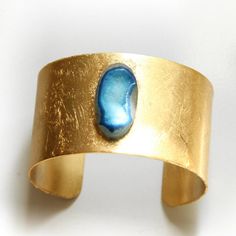 Blue Druzy Cuff Bracelet: a pretty, marine blue druzy gemstone is permanently bonded to a solid brass cuff.DETAILS:• Solid brass cuff • Agate druzy stone• 1.5" in width• Gold leafed cuff for pretty texture and shine(Due to the nature of the leafing process, the look is organic with a few irregularities in texture.)Thanks so much for visiting my shop!xo Memorable Jewelry, Gold Cuff Bracelet, Brass Cuff, Gold Bracelet Cuff, Gold Cuffs, Marine Blue, Druzy Agate, Druzy, Cuff Bracelet