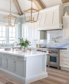 a large kitchen with an island in the middle and two lights hanging from the ceiling