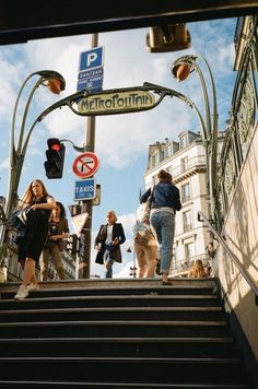 people walking up and down the stairs in front of a metro station with no parking sign