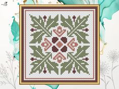 a cross - stitch pattern with flowers and leaves on the front, in a gold frame