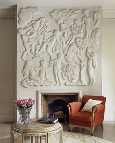 a living room filled with furniture and a large white sculpture on the wall above a fire place