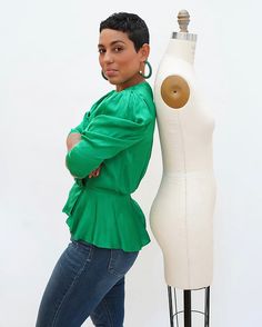 a woman standing next to a mannequin with her arms on the back of it