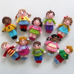 a group of knitted dolls sitting next to each other on a white table top