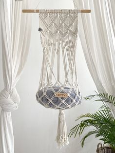 a hammock hanging from the ceiling in a room with curtains and potted plants