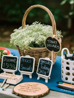 a picnic table with chalkboard signs and flowers in a basket next to other items