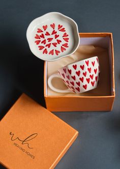 two cups with hearts painted on them in a box