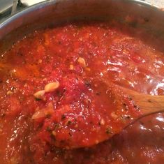 a wooden spoon in a pot filled with red sauce