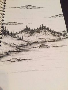 a pencil drawing of mountains and trees in the distance on a notepad with a pen