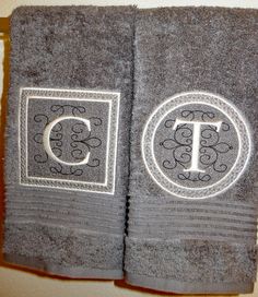 two gray towels with monogrammed letters on them